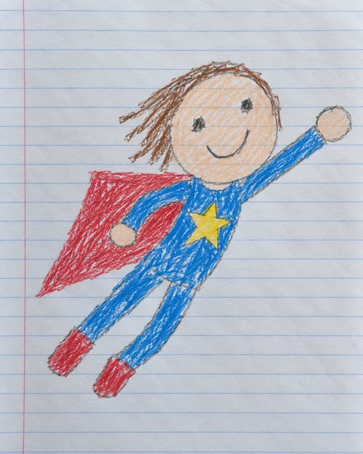 Drawing: A colored-pencil superhero girl with a red cape on lined notebook paper